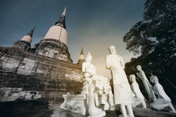 Ancient white buddha statues and ruined pagoda at Wat Yai Chai Mongkhon temple in Thailand.