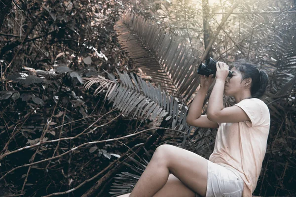 Jolie femme asiatique regardant avec des jumelles dans la forêt . — Photo