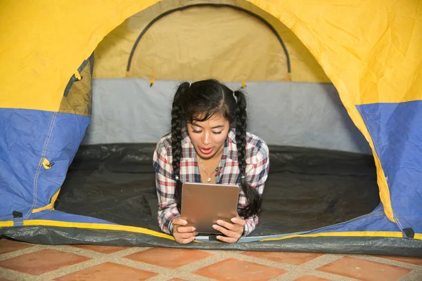 Bella donna asiatica sorridente sdraiata e alla ricerca tablet . — Foto Stock