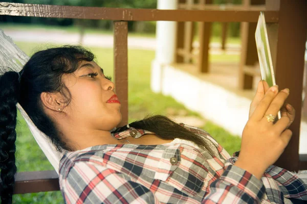 Graziosa asiatico donna lettura tablet su amaca  . — Foto Stock