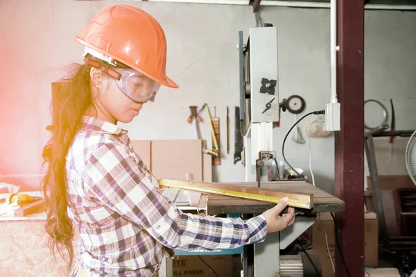 Asyalı güzel kadın marangoz ahşap için elektrikli zımpara kullanarak.