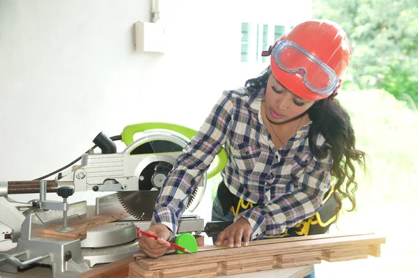 Pretty Asian carpenter woman is marking on wood. Stock Photo