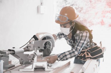 Asyalı güzel kadın marangoz ahşap için elektrikli zımpara kullanarak.