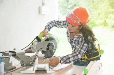 Asyalı güzel kadın marangoz ahşap için elektrikli zımpara kullanarak.