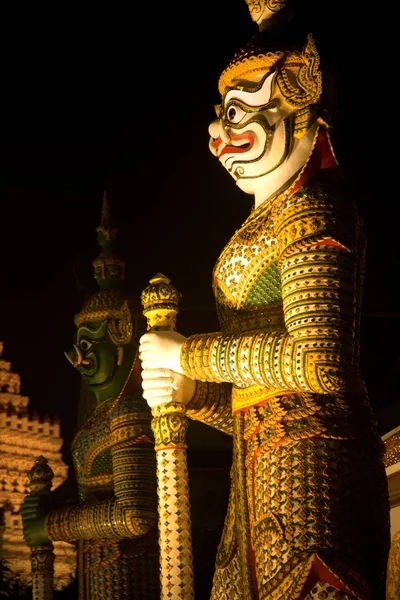 Nachtszene eines thailändischen Wächters am Eingang der Ordinationshalle in wat arun ratchawararam Tempel, Bangkok, Thailand. — Stockfoto