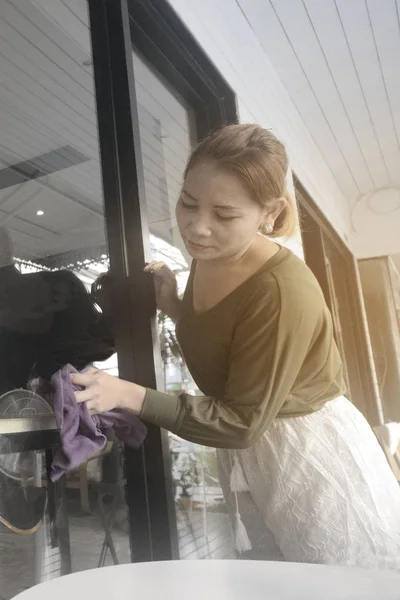 Asian piga eller hushållerska rengöring på glas skyltfönster. — Stockfoto