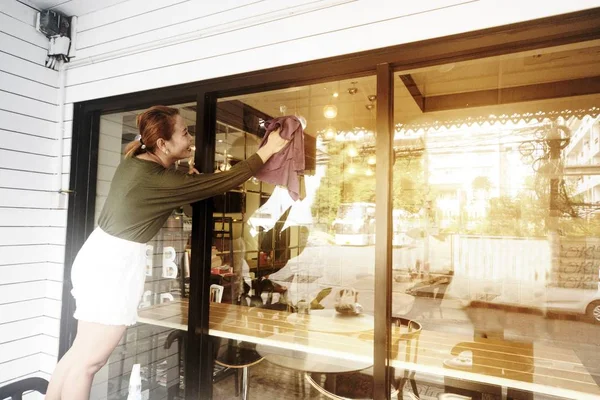 Asian maid or housekeeper cleaning on shop glass window. — Stock Photo, Image