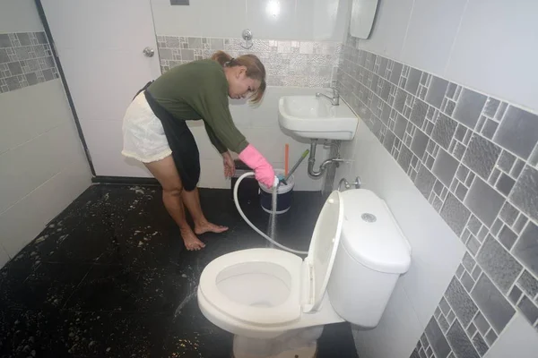 Asian female maid or housekeeper cleaning spray water on floor in toilet. — Stock Photo, Image