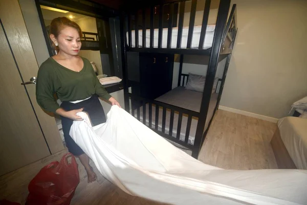 Unga asiatiska kvinnliga vandrar hem piga inrätta vitt täcke på lakan. — Stockfoto