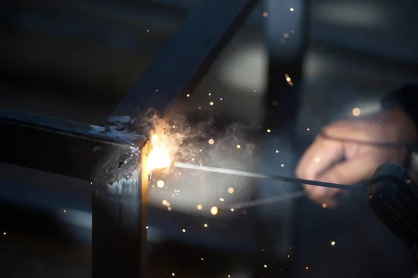 Worker is welding sparks table steel in factory.