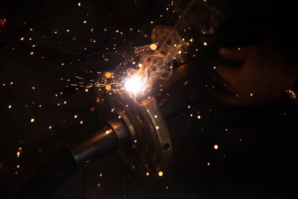 The worker is welding metal part of the details of the system rolling lifting gate. — Stock Photo, Image