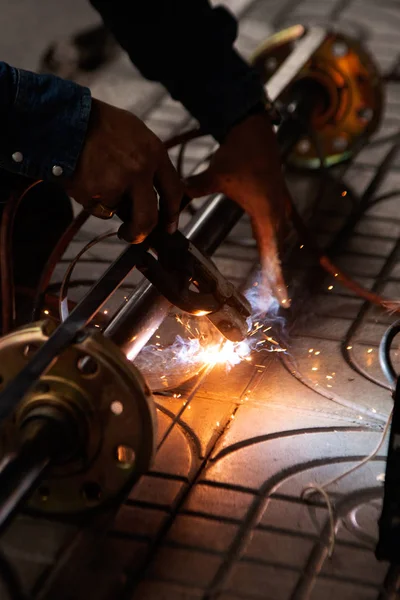 The worker is welding metal part of the details of the system rolling lifting gate. — Stock Photo, Image