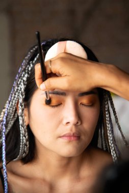 Makyaj sanatçısı Asyalı bir kadın için göz yazıyor..