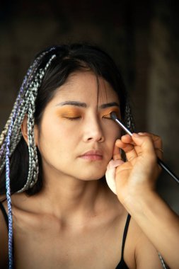 Makyaj sanatçısı Asyalı bir kadın için göz yazıyor..