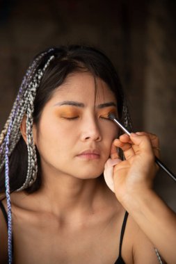 Makyaj sanatçısı Asyalı bir kadın için göz yazıyor..
