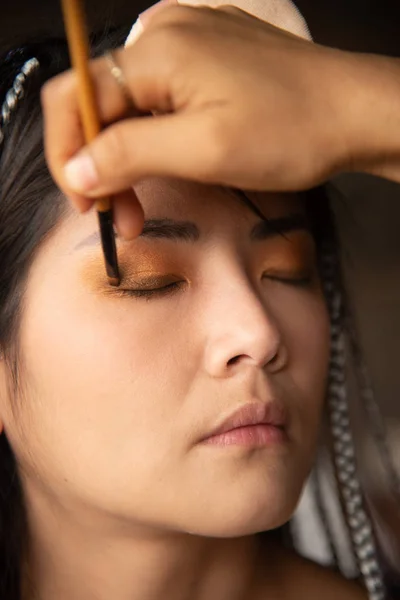 Maquiagem artista escrevendo olhos para uma mulher asiática . — Fotografia de Stock