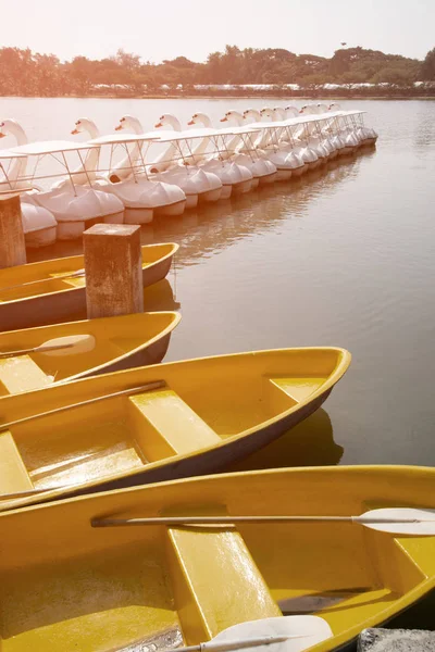 Żółta łódka i białe łabędzie łodzie Styl relaksu nad jeziorem w parku. — Zdjęcie stockowe