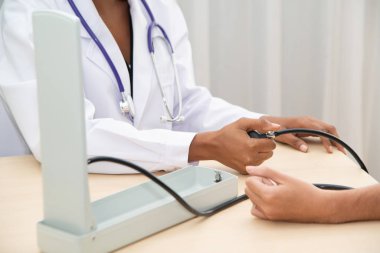 Kadın bir doktor, erkek hasta kanını ölçerek hastayı ölçüyor..