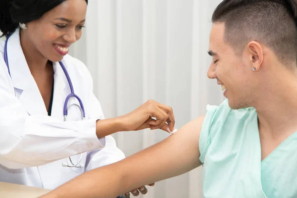 The African female doctor used a cotton swab to wipe the arm of the male patient before the injection.