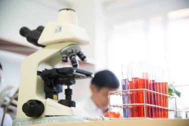 Tıbbi araştırma laboratuvarı ya da laboratuvar test örnekleri ya da bir pipetle çözelti ve arka planda mikroskop bulunan 96 iyi hücre tepsisi.. 