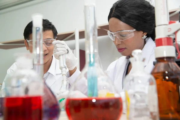Två forskare arbetar i laboratoriet. Unga kvinnliga forskare och hennes senior handledare gör utredningar på laboratorieutrustning. — Stockfoto