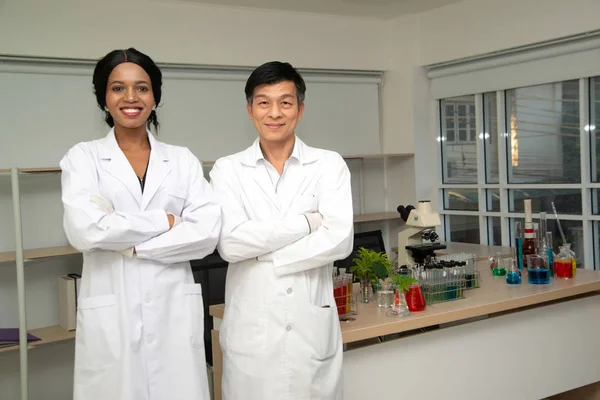 Leende grupp av forskare i moderna laboratoriet, blanda team av vetenskapliga forskare i lab bär vita rockar. — Stockfoto