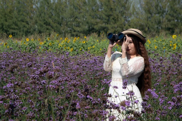 Asiatique jolie femme debout et regarder une jumelle dans la verveine de fleur bonariensis jardin et lecture joyeusement dans différents gestes heureusement . — Photo