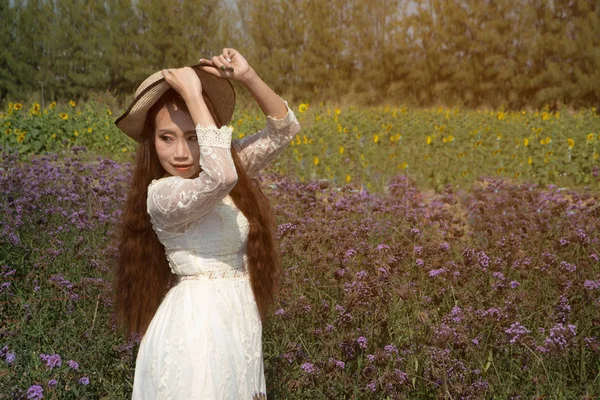 Asiática bonita mujer de pie en un jardín de flores verbina bonariensis y divertirse en diferentes gestos Felizmente . —  Fotos de Stock