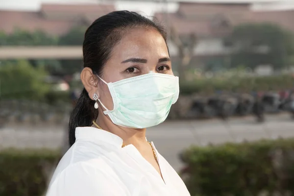 Aziatische vrouw dragen een Corona Virus en minuut stof pm 2,5 bescherming masker staan op de markt. — Stockfoto