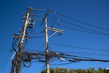 Elektrik kabloları ve kablolar direğe bağlandı. Bangkok, Tayland 'da arka planda mavi gökyüzü ile karışık görünüyor.. 