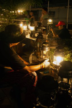 NAKORN PATHOM, THAILAND - 22 Şubat 2020: Kimliği belirsiz erkek Tayland 'ın Nakorn Pathom Eyaleti' ndeki Don Wai yüzer marketinde 2020 Kasırga Lambası 'nda gösterilecek olan eski lambayı tamir ediyor..