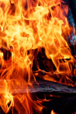 Şöminede yakın çekimde odun yanıyor. Sıcak turuncu şenlik ateşi ve odun parçaları.