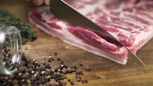 Шеф-кухар розрізає шматки сирого бекону гострим ножем на дерев'яній дошці — стокове відео