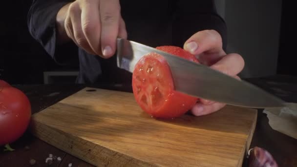 Chef corta tomate rojo maduro en círculos en la tabla de madera — Vídeo de stock