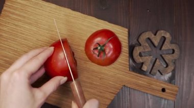Şef ahşap tahtada domates keskin çelik bıçağı keser.