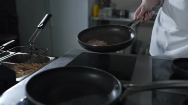 Şef, restoranın mutfağındaki sıcak tavaya biftek fırlatıyor.