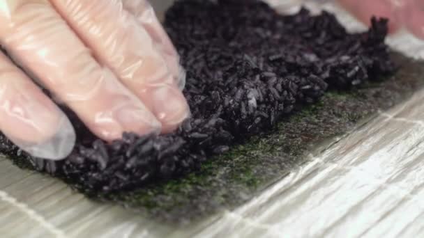 Chef mette riso nero su nori e fa rotolare il sushi al rallentatore — Video Stock