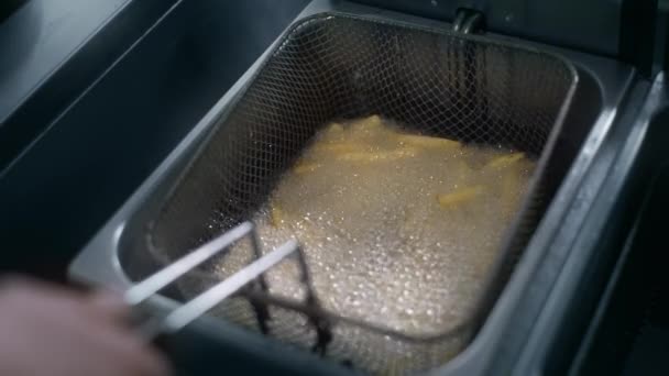 Шеф-повар кладет сырой картофель в кипящее масло для приготовления картошки фри в замедленной съемке — стоковое видео