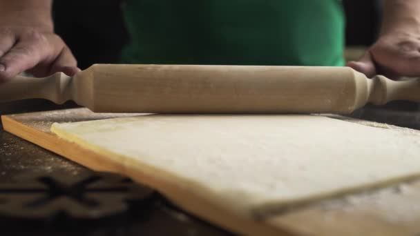 Шеф-повар выкатывает тесто со скалкой на кухонном столе — стоковое видео