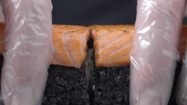 Шеф-кухар розпадається навпіл суші рол з чорним рисом і лососем — стокове відео