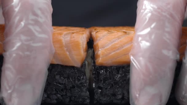 Chef divide in due il rotolo di sushi con riso nero e salmone — Video Stock