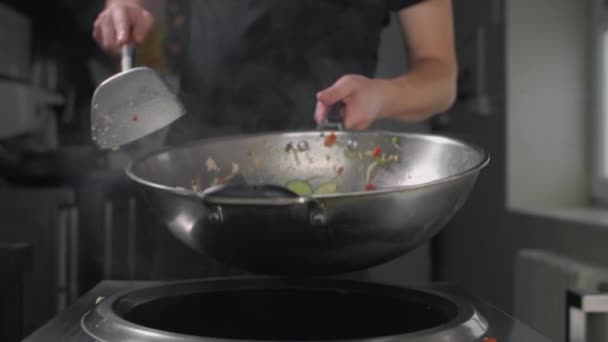 Chef lanza verduras fritas con fideos en wok caliente en cámara lenta — Vídeo de stock