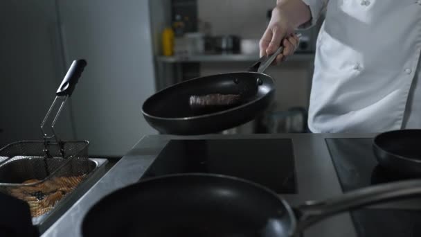 Chef lanza carne asada en la sartén caliente en la cocina del restaurante en cámara lenta — Vídeo de stock