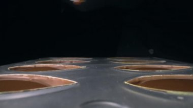 Çikolata kalıplarını pralin için sıvı çikolatayla doldurur.