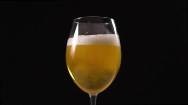 Altın köpüklü bira bardağa ağır çekimde dökülür.