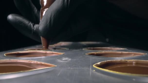 Chocolatier enche moldes de chocolate com recheio de chocolate líquido para praline — Vídeo de Stock