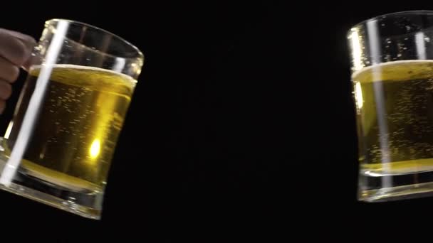 Kloppende bierbekers met licht gouden bier in slow motion — Stockvideo