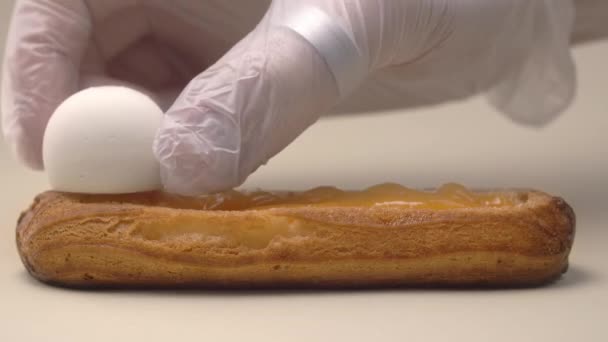 Кондитер добавляет сливочные сырные шарики в эклер, делая десерт — стоковое видео