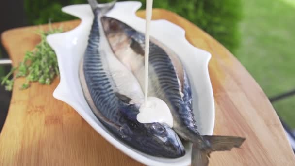 Salsa de crema se vierte en la caballa cruda cocinar harina de pescado — Vídeos de Stock