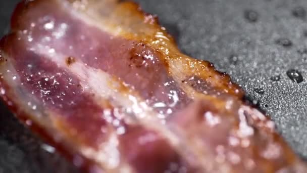 Pedaços crocantes de bacon saboroso é frito na panela quente Videoclipe